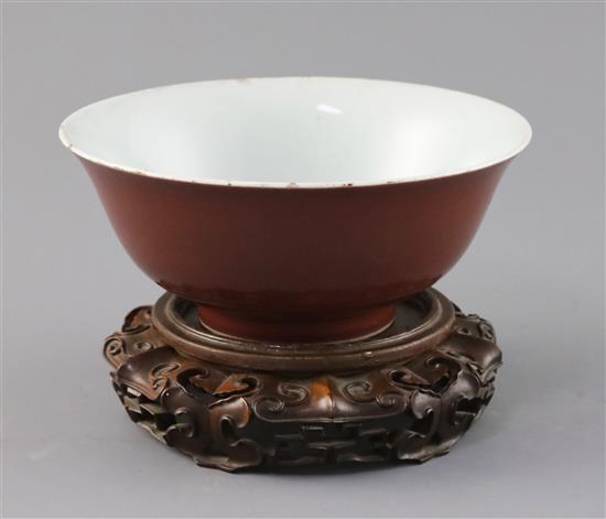 A Chinese copper red glazed bowl, Qianlong seal mark and of the period (1736-95), D. 18.2cm, small rim chips, wood stand